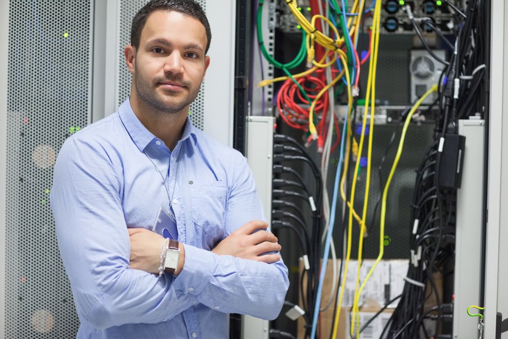 Man standing with arms crossed in data center in front of servers