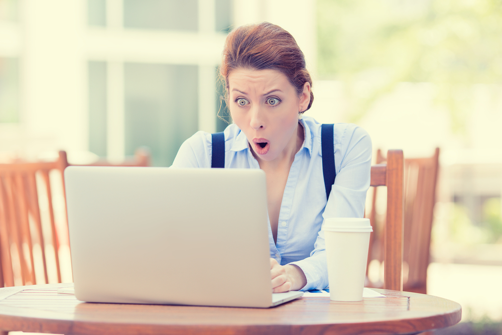 Shocked young business woman using laptop looking at computer screen blown away in stupor sitting outside corporate office. Human face expression, emotion, feeling, perception, body language, reaction-1