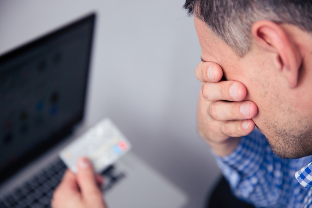 Upset man holding credit card with laptop on background-1-1