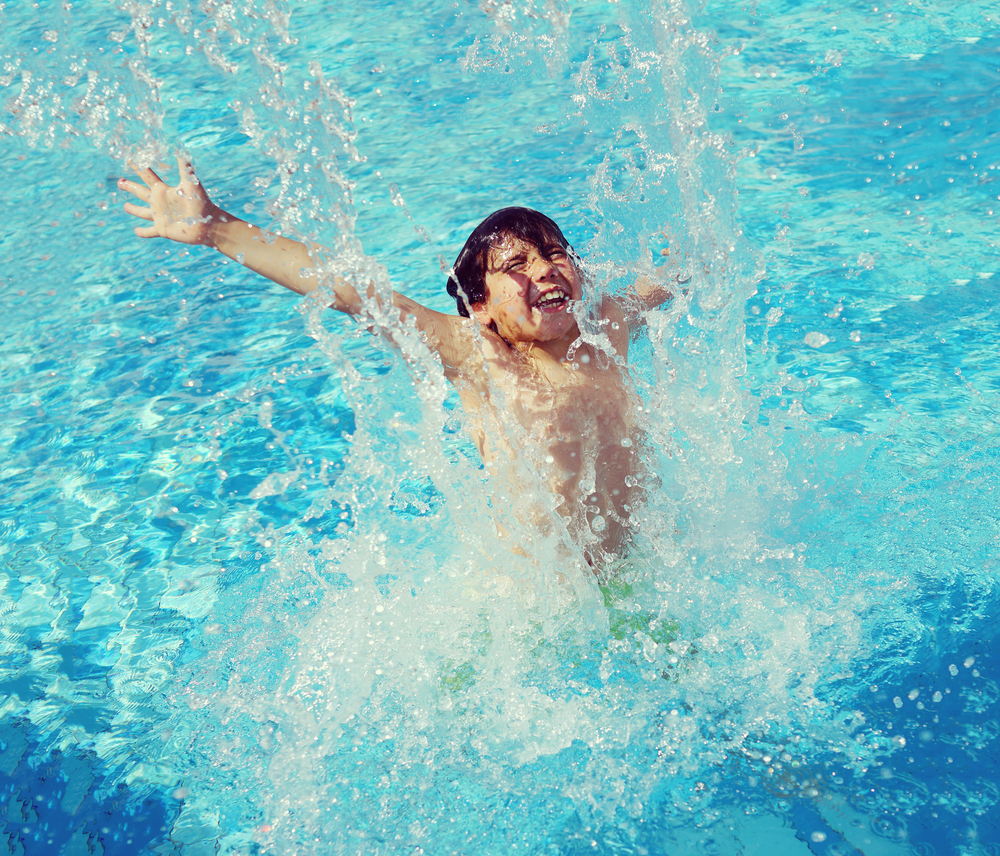 Child splashing in summer water pool
