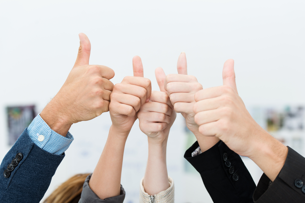 Successful diverse young business team giving a victorious thumbs up to show their success and motivation, close up view of their raised hands